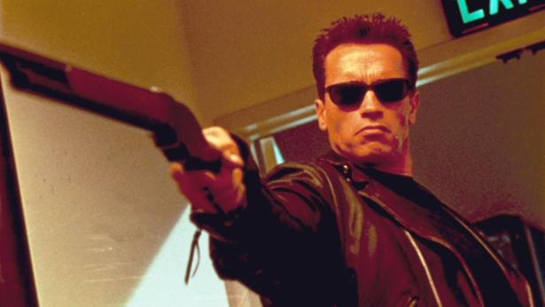 Arnold Schwarzenegger als Terminator mit Sonnenbrille und Waffe.