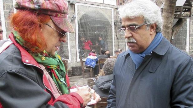 Eine Frau mit rotem Haar gibt einem Mann mit Brille ein Autogramm.