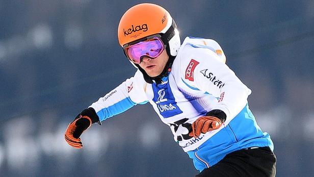 Ein Skirennfahrer mit orangefarbenem Helm und Skibrille während eines Rennens.
