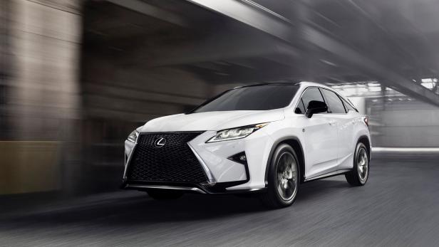 Ein weißer Lexus RX fährt auf einer Straße entlang.