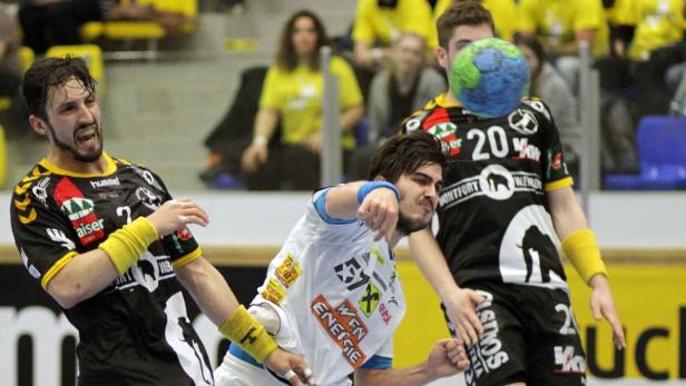 Zwei Handballspieler kämpfen um den Ball während eines Spiels.