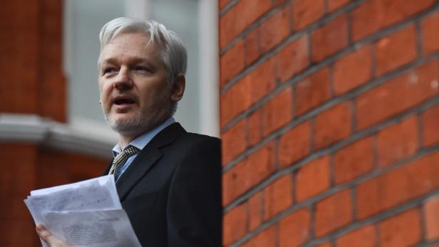 Julian Assange hält Dokumente in der Hand und spricht.