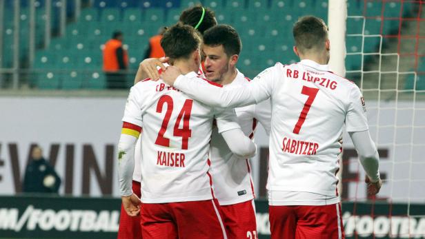 Fußballspieler von RB Leipzig umarmen sich auf dem Spielfeld.