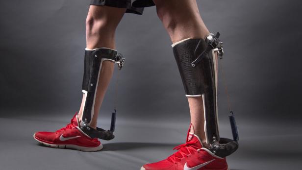 Ein Mann trägt an beiden Beinen Karbon-Orthesen und rote Nike-Schuhe.