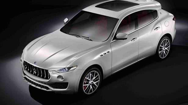 Ein silberner Maserati Levante mit roter Innenausstattung vor dunklem Hintergrund.