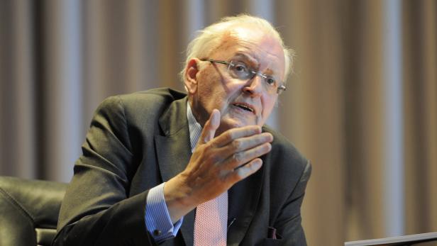 Ein älterer Mann mit Brille gestikuliert während einer Rede.