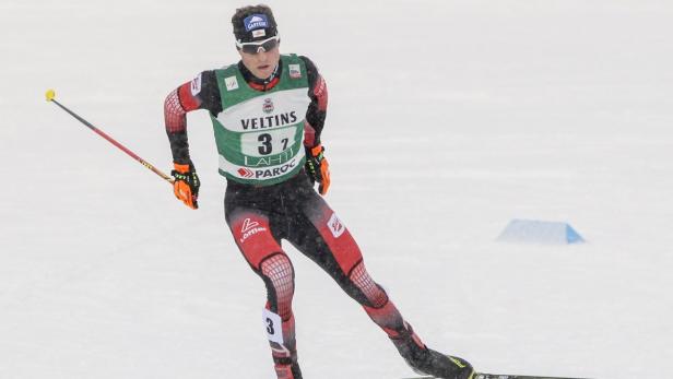 Ein Skilangläufer mit der Startnummer 32 in roter und schwarzer Sportbekleidung.