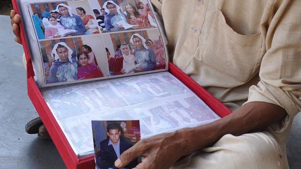 Ein Mann betrachtet ein Fotoalbum mit Hochzeitsbildern.