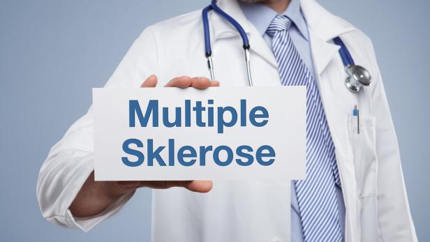 Ein Arzt hält ein Schild mit der Aufschrift „Multiple Sklerose“.