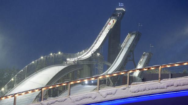Die schneebedeckten Skisprungschanzen von Lahti in Finnland sind nachts beleuchtet.