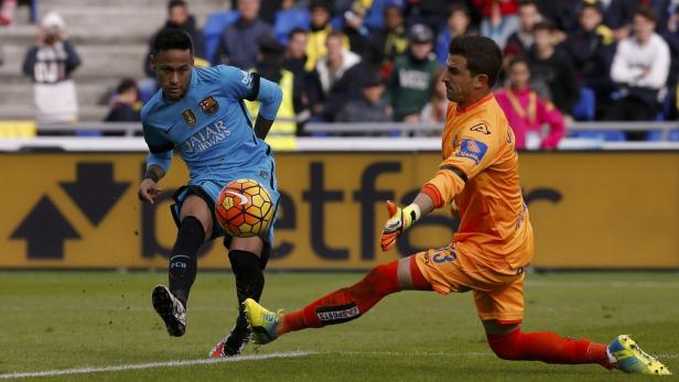 Neymar schießt den Ball, während der Torwart versucht, ihn abzuwehren.