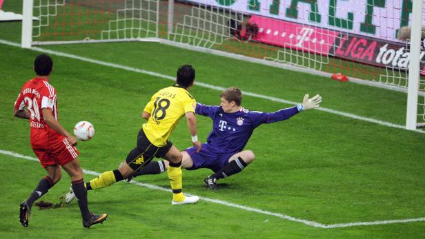 Ein Fußballspieler schießt auf das Tor, während der Torwart versucht, den Ball abzuwehren.