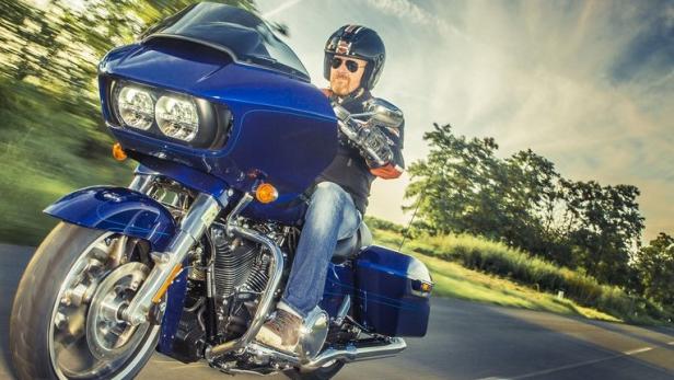Ein Mann fährt mit einem blauen Motorrad auf einer Landstraße.