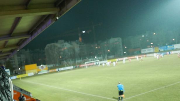 Blick von der Tribüne auf ein Fußballspiel bei Nacht.