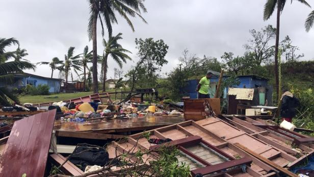 Nach einem Sturm liegen Trümmer und persönliche Gegenstände verstreut in einer tropischen Gegend.