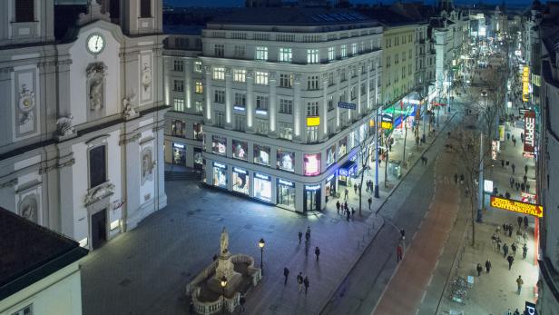Blick auf die belebte Kärntner Straße in Wien bei Nacht.
