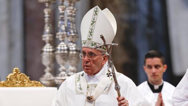 Papst Franziskus hält ein Kreuz in der Hand.