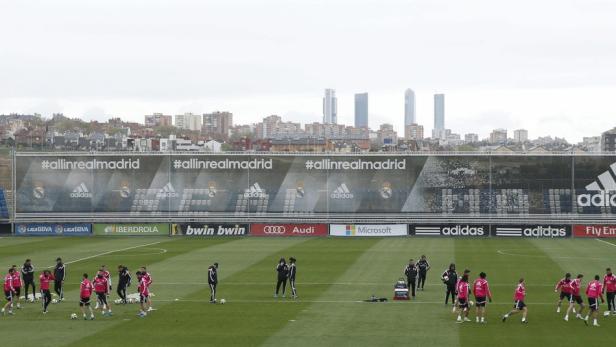 Fußballspieler trainieren auf dem Trainingsplatz von Real Madrid vor der Skyline der Stadt.