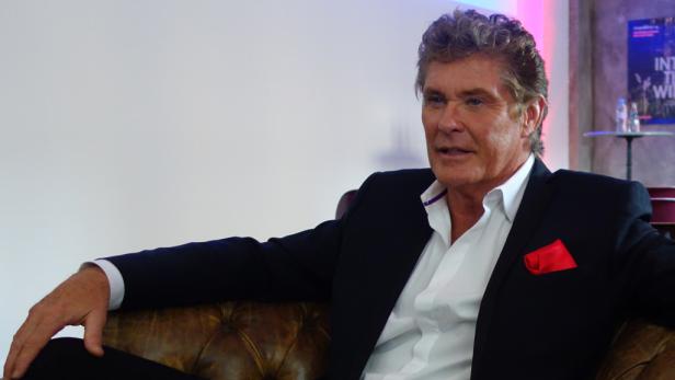 David Hasselhoff sitzt in einem Sessel und lächelt.