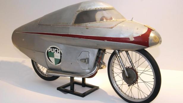 Ein windschnittiges Puch-Motorrad mit stromlinienförmiger Karosserie steht auf einem Sockel.