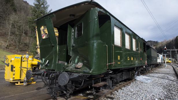 Ein beschädigter, grüner Eisenbahnwaggon steht auf einem Gleis.