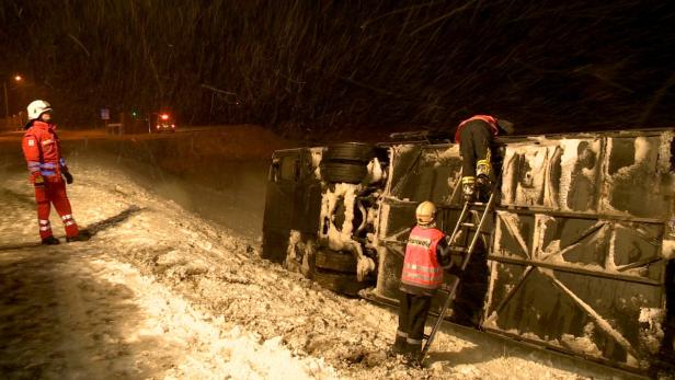 Bei starkem Schneefall untersucht die Feuerwehr einen umgestürzten Lastwagen.