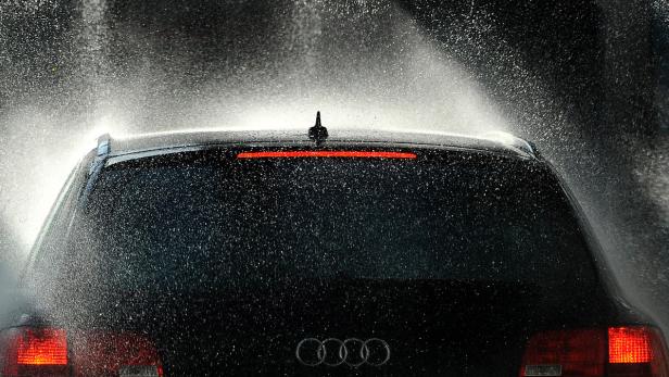 Ein schwarzer Audi wird in einer Waschanlage mit Wasser besprüht.