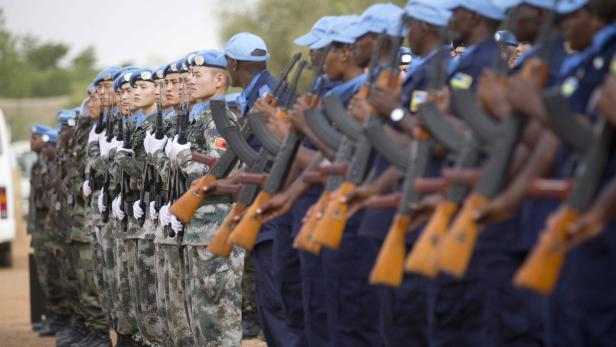 Eine Reihe von UN-Friedenstruppen steht mit Gewehren in Formation.