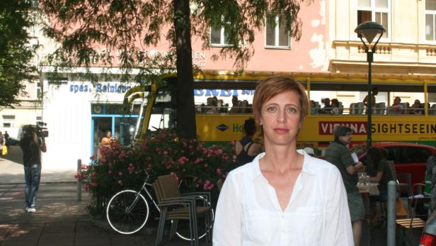 Eine Frau steht vor einem gelben Sightseeing-Bus in Wien.