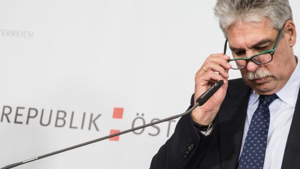 Ein Mann mit Brille steht vor einem Mikrofon der Republik Österreich.