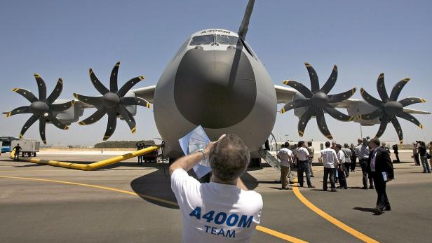 Ein Airbus A400M Militärtransporter steht auf einem Flugfeld, umringt von Menschen.