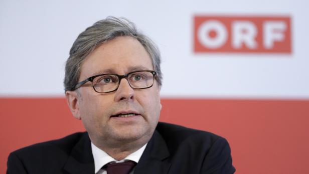 Ein Mann mit Brille und dunklem Anzug vor dem ORF-Logo.