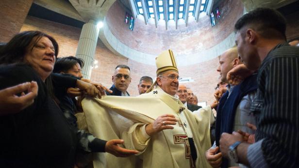 Papst Franziskus interagiert mit Menschen in einer Kirche.