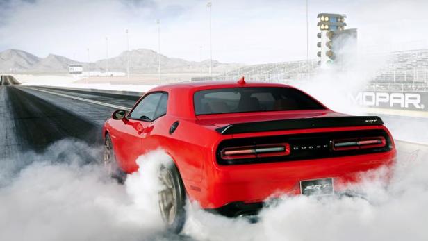 Ein roter Dodge Challenger SRT macht auf einer Rennstrecke einen Burnout.