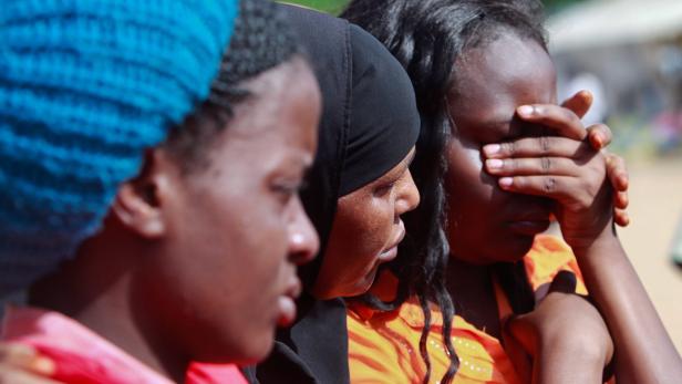 Drei Frauen stehen nebeneinander, eine weint und verdeckt ihr Gesicht.