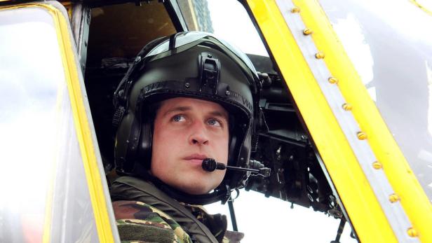 Prinz William im Cockpit eines gelben Hubschraubers mit Helm und Mikrofon.