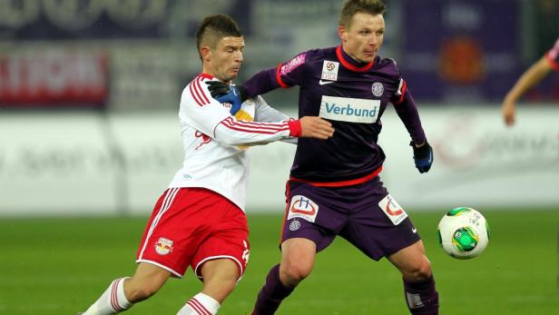 Zwei Fußballspieler kämpfen um den Ball auf dem Spielfeld.