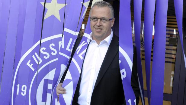 Ein Mann mit Brille steht vor einem lila Banner des Fußballklubs Erzgebirge Aue.
