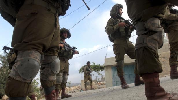 Eine Gruppe von Soldaten patrouilliert mit Gewehren in einer städtischen Umgebung.