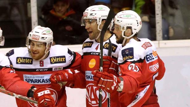 Drei Eishockeyspieler in rot-weißen Trikots feiern gemeinsam.