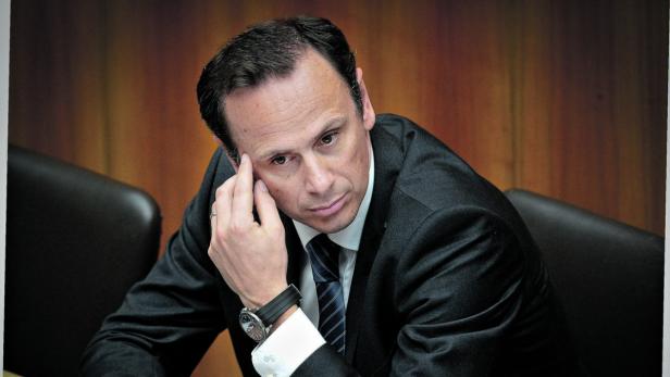 Ein Mann im Anzug sitzt nachdenklich da und stützt seinen Kopf.