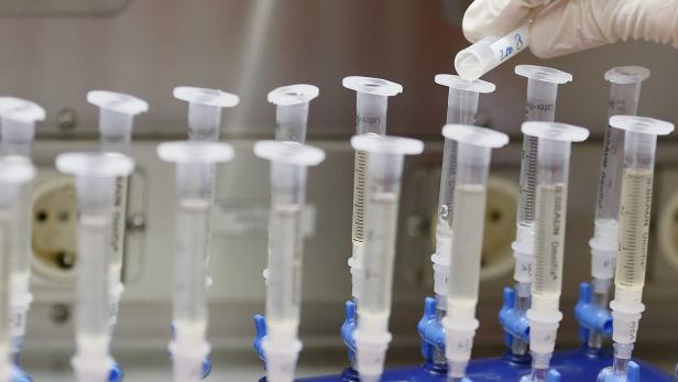Eine Hand mit Handschuh gießt eine Flüssigkeit in ein Röhrchen in einem Labor.