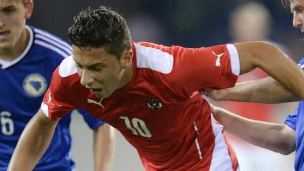 Ein österreichischer Fußballspieler im roten Trikot mit der Nummer 10 im Zweikampf.