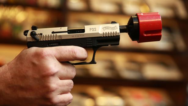 Eine Hand hält eine Walther P22 Schreckschusspistole mit einem roten Aufsatz.