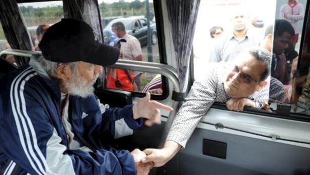 Fidel Castro schüttelt einem Mann die Hand, der aus einem Busfenster schaut.