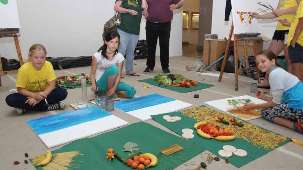 Kinder malen Bilder mit Obst und Gemüse als Vorlage.