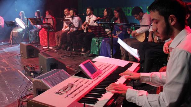 Eine Musikgruppe tritt auf einer Bühne mit verschiedenen Instrumenten auf.