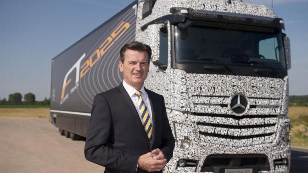 Ein Mann im Anzug steht vor einem mit Mustern beklebten Mercedes-Benz Future Truck 2025.