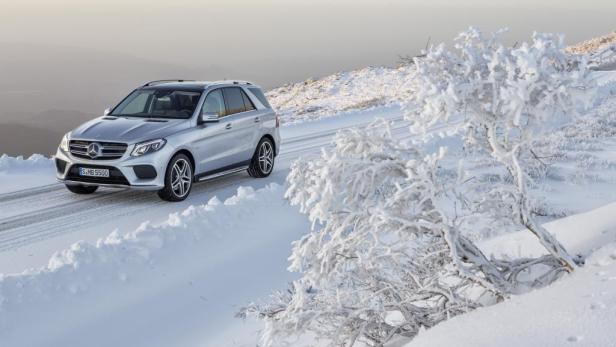 Ein silberner Mercedes-Benz fährt auf einer schneebedeckten Straße.