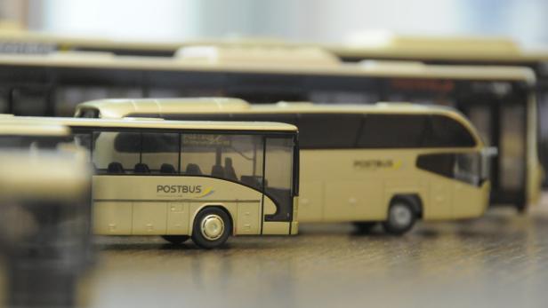 Mehrere Modellbusse der Marke Postbus stehen auf einer Oberfläche.